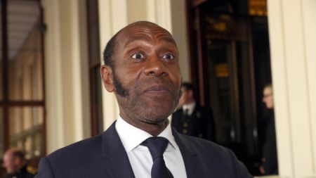 Lenny Henry in a black suit caught at the camera.